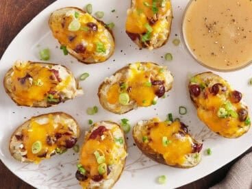 Overhead view of thanksgiving potato skins on a plate with a small bowl of gravy.